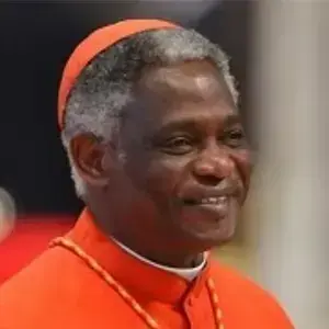 Cardinal Peter Turkson smiles, wearing a red cassock and skullcap.
