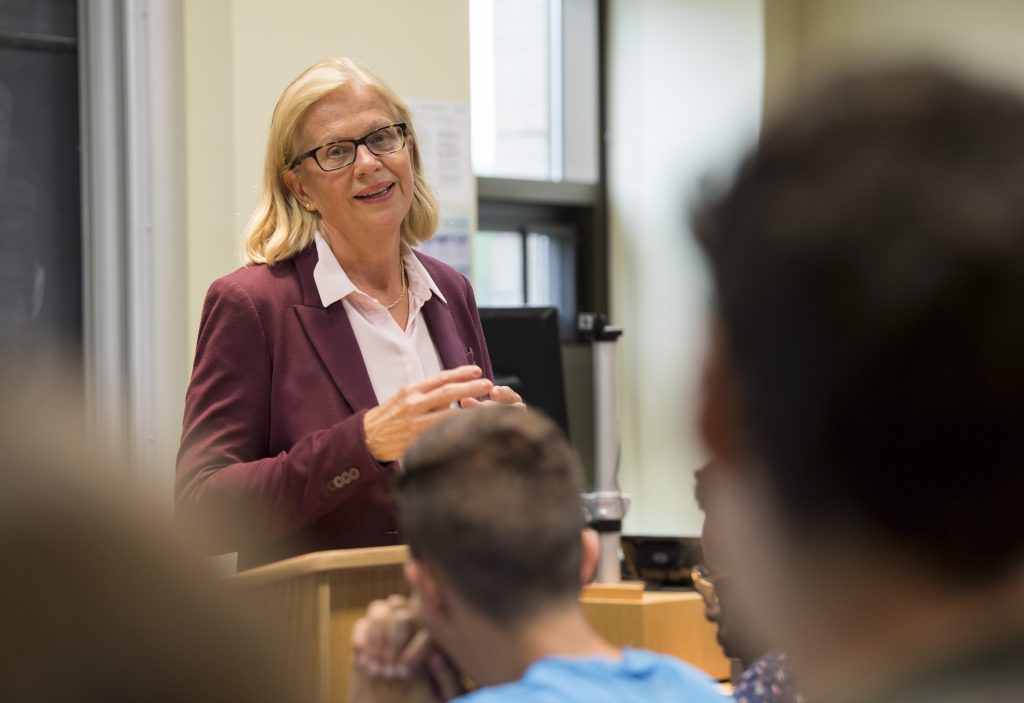 Norwegian diplomat speaks to students behind a podium in classroom