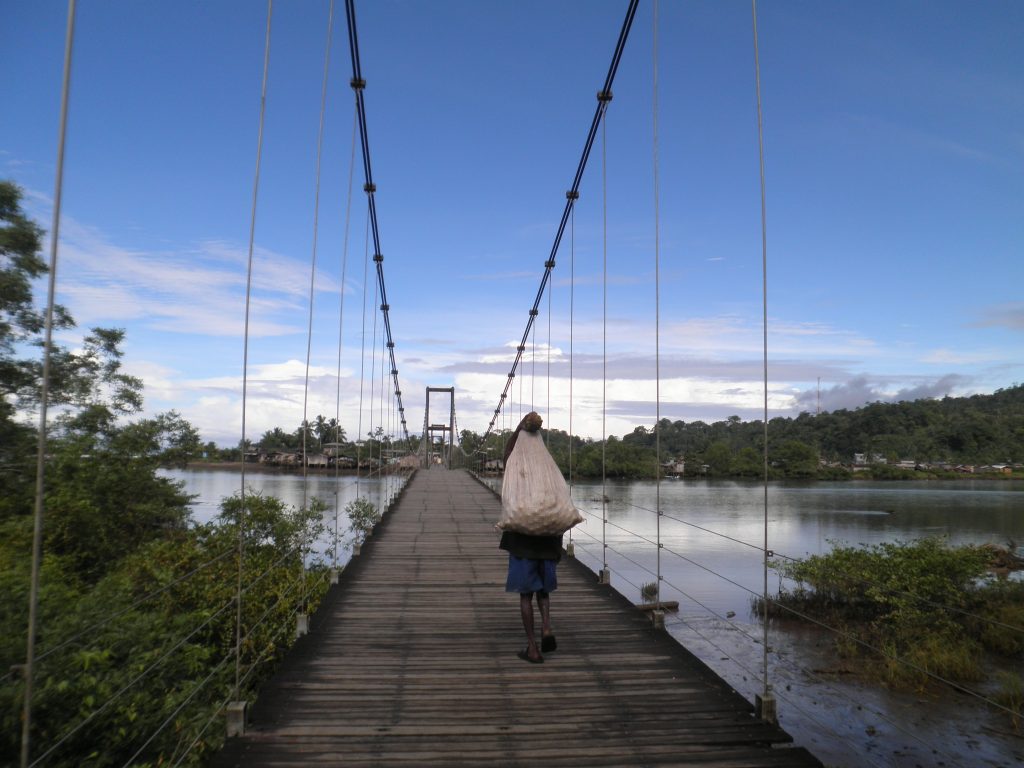 Colombian walking across a bridge over water
