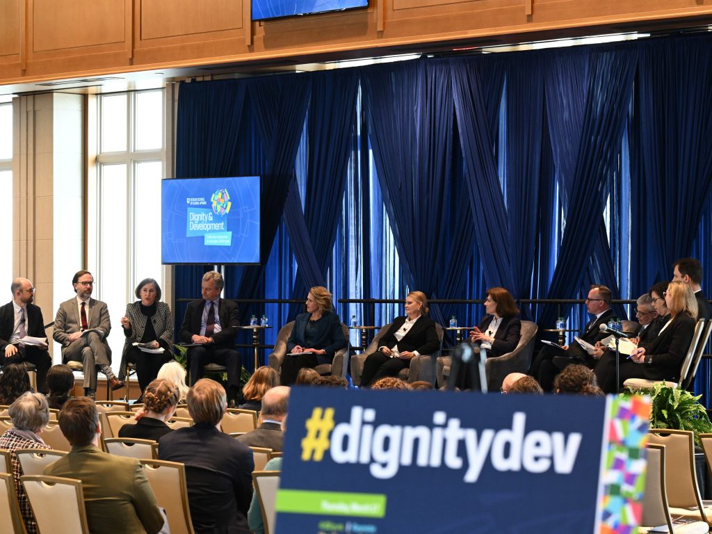 Panelists sit on stage at the Dignity and Development Forum to discuss global fragility
