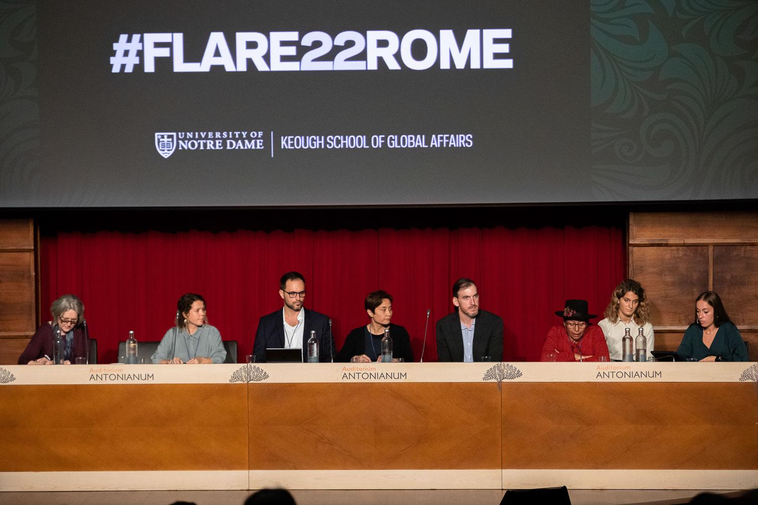 A panel of 8 speakers addresses with a background drop reading #FLARE22ROME