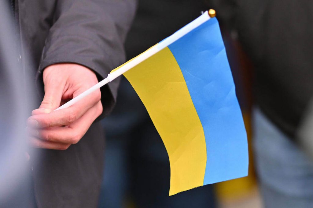 photo of hand holding small Ukrainian flag