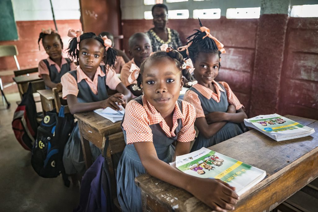 Haitian school girls seated at classroom desks and smiling